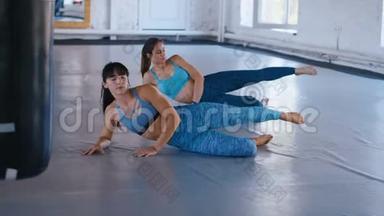 两个女运动员在<strong>健身</strong>馆锻炼腹部。女运动员正在练习普拉提以<strong>增</strong>强<strong>肌</strong>肉